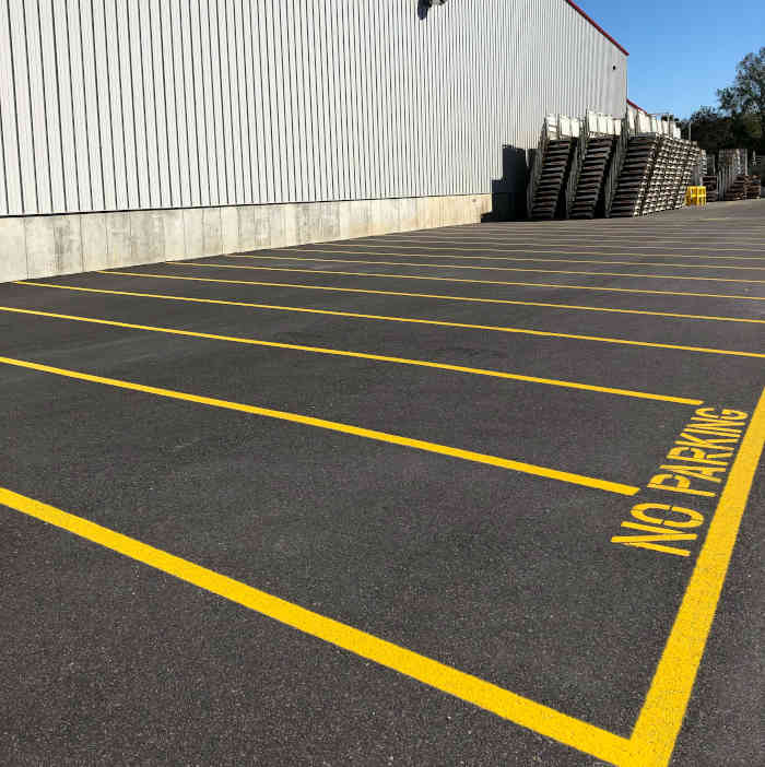 Asphalt parking lot which has just been striped with yellow lines. 